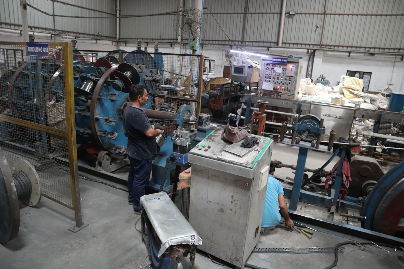 Operator at the armouring line beside the 80 mm extruder control panel