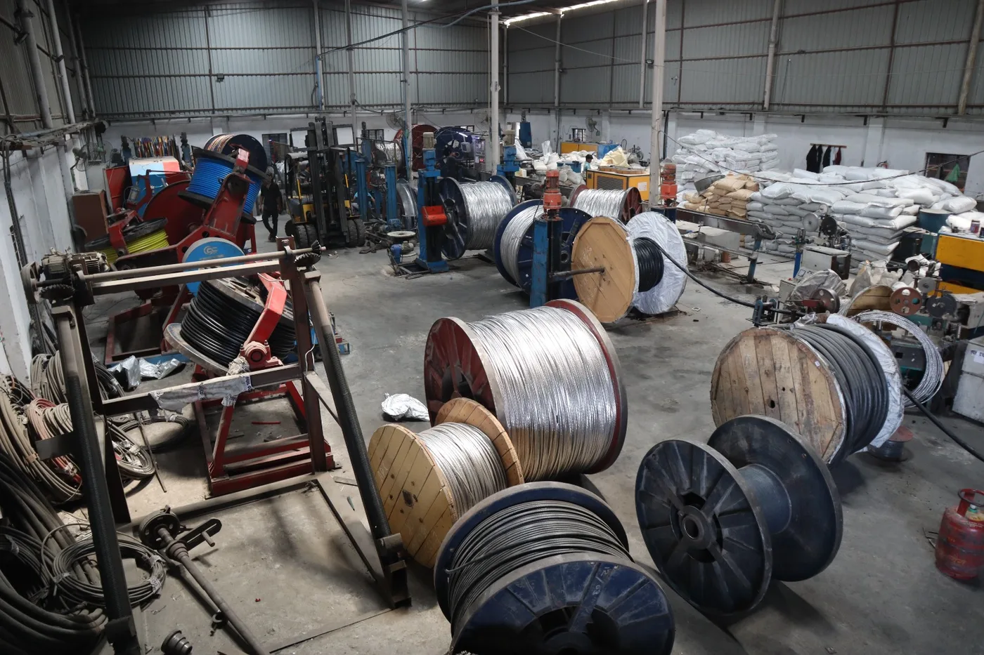 Cable drums and reels across the extrusion bay, with PVC compound sacks stacked along the wall